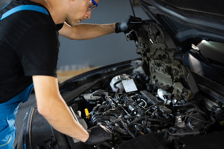 618故障摄影照片_汽车修理工在车库打开汽车引擎盖发动机维修期间注意到维修零件。
