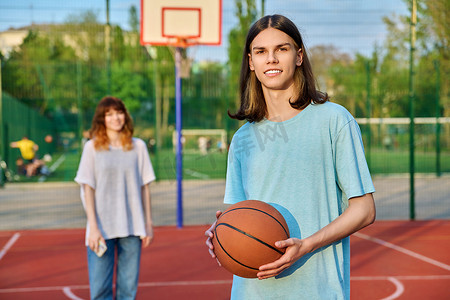 年轻人在户外游戏场打篮球的肖像，女孩失去了焦点。