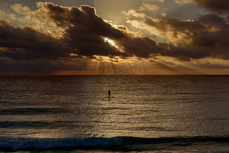 黎明时分，一个男人在海上冲浪的剪影。