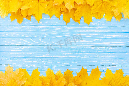 边框黄色背景摄影照片_秋叶框架在木质背景顶视图秋季边框黄色和橙色叶子复古木桌复制文本空间。