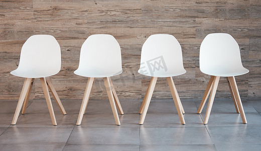 办公椅背景摄影照片_招聘员工招聘活动、面试等候室和空木墙背景中的四把白色办公椅。