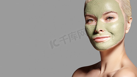 美丽的女人应用绿色面膜。