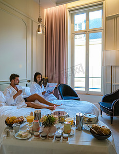 法国的卧室摄影照片_早上在巴黎的床上醒来，享用早餐咖啡和报纸，男人和女人 honymoon