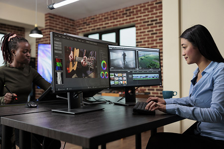 视频编辑软件摄影照片_创意机构专业视频编辑坐在办公桌前使用专业软件