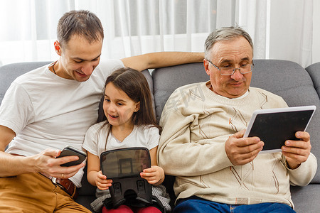 感恩节送礼摄影照片_祖父和孙女，父亲家里有智能手机