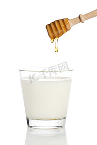 黄色液体摄影照片_蜂蜜从蜂蜜勺滴到装有牛奶的罐子里