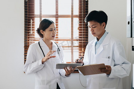 亚洲女医生和男医生在治疗前使用平板电脑讨论患者问题的肖像
