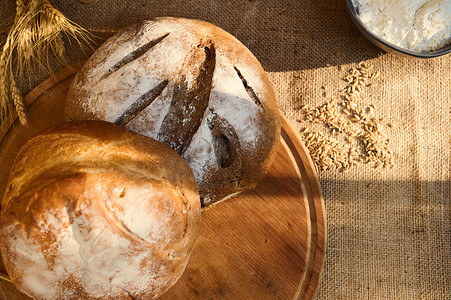 麻布桌布上的木板上放着各种新鲜出炉的自制美味全麦杂粮面包