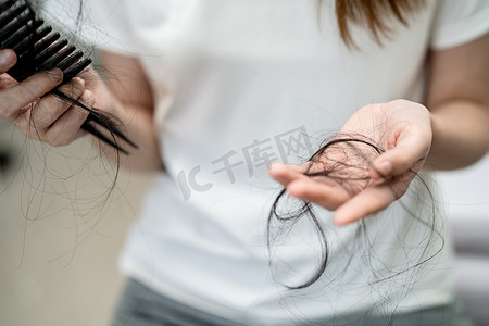 秃顶摄影照片_亚洲女性有长脱发问题，头发附着在梳子上。