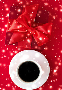 寒假礼盒、咖啡杯和红色平底背景上的发光雪，圣诞礼物惊喜