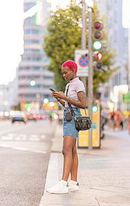 非洲裔年轻女子站在街上使用手机