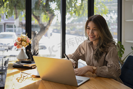 女访谈摄影照片_性格开朗的年轻女子在笔记本电脑上与她的商业伙伴进行视频会议。