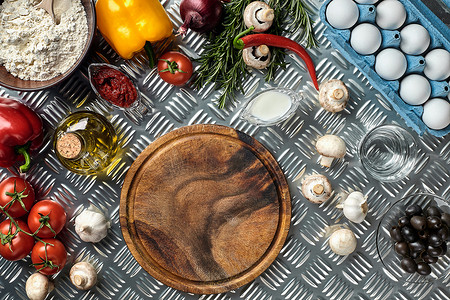 比萨原料摄影照片_用传统的比萨准备原料切割木板：蘑菇、西红柿酱、罗勒、橄榄油、奶酪、香料。