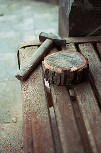 一把旧的老式锤子和一条长凳上放着锯末的圆松木条。