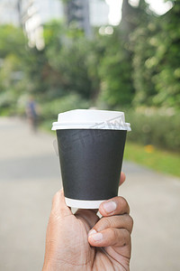 手办包装摄影照片_在户外拿着外卖纸咖啡杯
