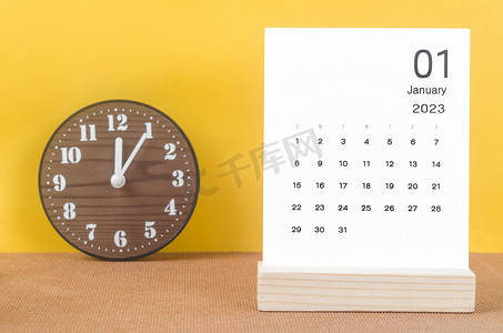 2023 年 1 月 2023 年月历，黄色桌子上有时钟。