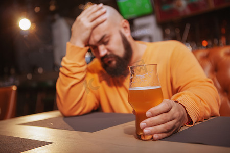 喝啤酒摄影照片_留胡子的男人在酒吧喝啤酒