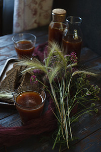 传统的自制饮料克瓦斯装在玻璃杯和瓶子里，配有黑麦和西洋蓍草的夏季花束。