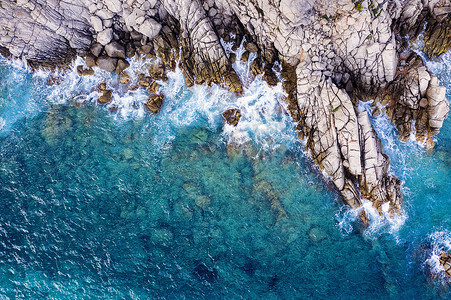 清澈蔚蓝的大海中岩石悬崖的空中俯视图