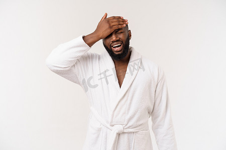 抑郁症背景摄影照片_年轻的非洲裔美国男子穿着浴袍，在孤立的白色背景下思考，看起来疲惫不堪，对抑郁症问题感到厌倦。