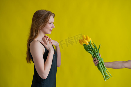 郁金香女孩摄影照片_白人妇女接受郁金香作为黄色背景的礼物。