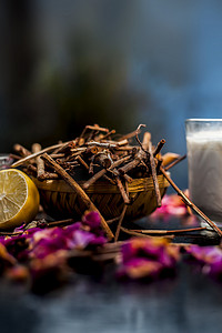 桂花摄影照片_黑色木质表面上的曼吉斯塔或印度茜草根面膜，由曼吉斯塔根粉、柠檬、牛奶和一些精油组成。
