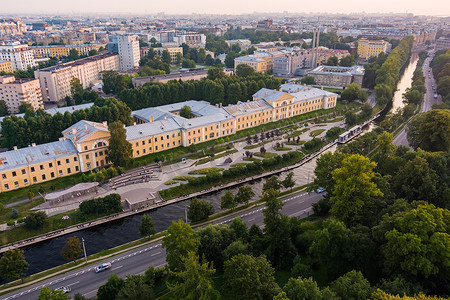 河堤公园摄影照片_俄罗斯日落时圣彼得堡卡尔波夫卡河堤公园的鸟瞰图、休闲区、长凳和露天剧场、公园对面的植物园