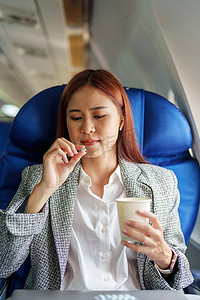 一位成功的亚洲女商人或企业家在商务舱的飞机上穿着正式西装，在飞行期间服用晕车药的肖像