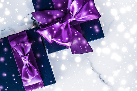 冬季节日礼盒，配有紫色丝绸蝴蝶结、大理石背景上的雪花，作为豪华美容品牌的圣诞和新年礼物，平铺设计