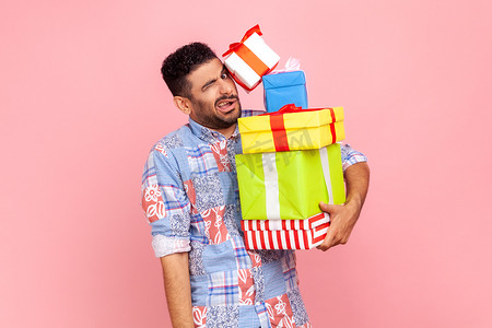滑稽的留着胡子的男人的肖像，手里拿着很多沉重的礼物盒落在他身上，皱着眉头，试图拿着许多生日礼物。