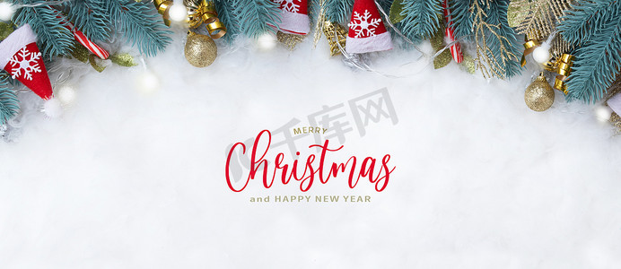 金色雪花背景图摄影照片_横幅上有圣诞快乐的文字和冷杉树枝圣诞装饰品平铺在雪背景上