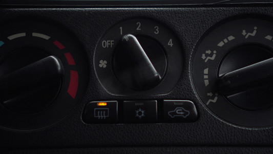 温度按钮摄影照片_女子打开风扇，按下车内车窗加热按钮。