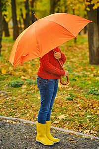 橙色伞下滑稽的无法辨认的孩子