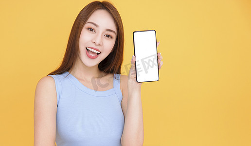 黄色背景中显示手机空白屏幕的快乐亚洲女性