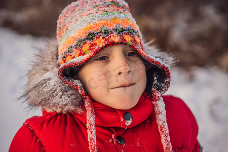 下雪玩耍摄影照片_穿着红色时尚衣服的男孩在户外玩耍。