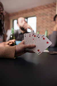 同舟共济共同抗疫摄影照片_白人女性手持纸牌游戏的特写镜头，同时与朋友一起享受有趣的休闲活动。