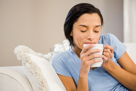 平静的黑发女人用白杯喝酒