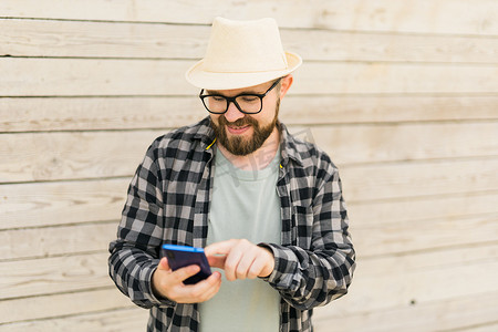 夏季城市突破木墙时，微笑的男性游客使用智能手机 — 技术和社交媒体应用概念