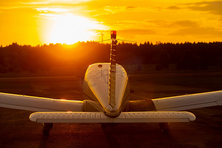日落背景上停放的小飞机的后视图。