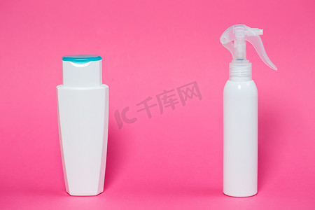 皮肤喷雾摄影照片_两个白色瓶子，里面有洗发水、身体凝胶、粉红色背景的皮肤喷雾