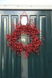 圣诞花环红色摄影照片_门上装饰着浆果圣诞花环