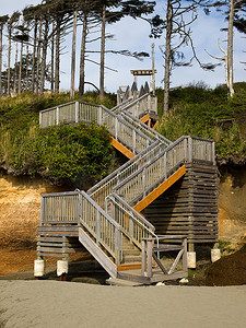 繁茂的树木摄影照片_沿着树木繁茂的山坡通往海滩的木楼梯