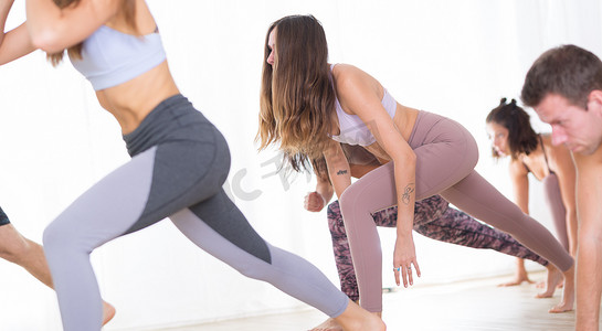 一群年轻的运动美女在瑜伽馆里，与教练一起练习瑜伽课，锻炼后站立、伸展和放松。