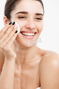 美容护肤概念-美丽的女人用棉签清洁她的脸-在白色背景和微笑。