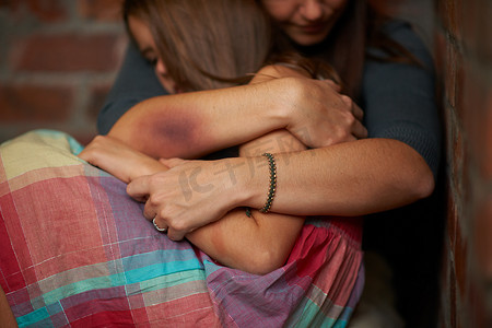 没事的……受虐待的女人拥抱她受惊的女儿。