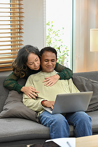 老人技术摄影照片_快乐的重试夫妇享受在家里共度时光并使用笔记本电脑。