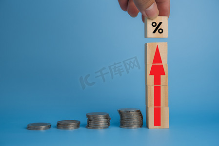 红色金融投资摄影照片_商业金融投资经济堆叠硬币通货膨胀和箭头红色与桌子上的木立方体。