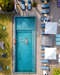 无人机从空中俯瞰塞舌尔普拉兰岛的泳池，在安斯沃尔伯特热带岛屿海滩的豪华度假村度假期间，泳池里的男女情侣，那里有海滩和棕榈树，