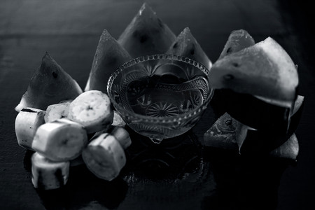 香蕉和西瓜摄影照片_西瓜面膜或面膜放在玻璃碗中的木质表面上，以及切成三角形的西瓜片，由西瓜和香蕉组成。用于即时自然发光。