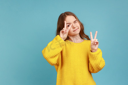 小女孩的肖像用双指展示 V 形手势，打手势胜利，庆祝成功。
